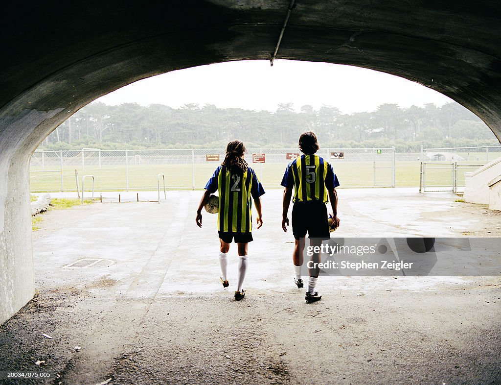 Soccer players walking out of tunnel, rear view