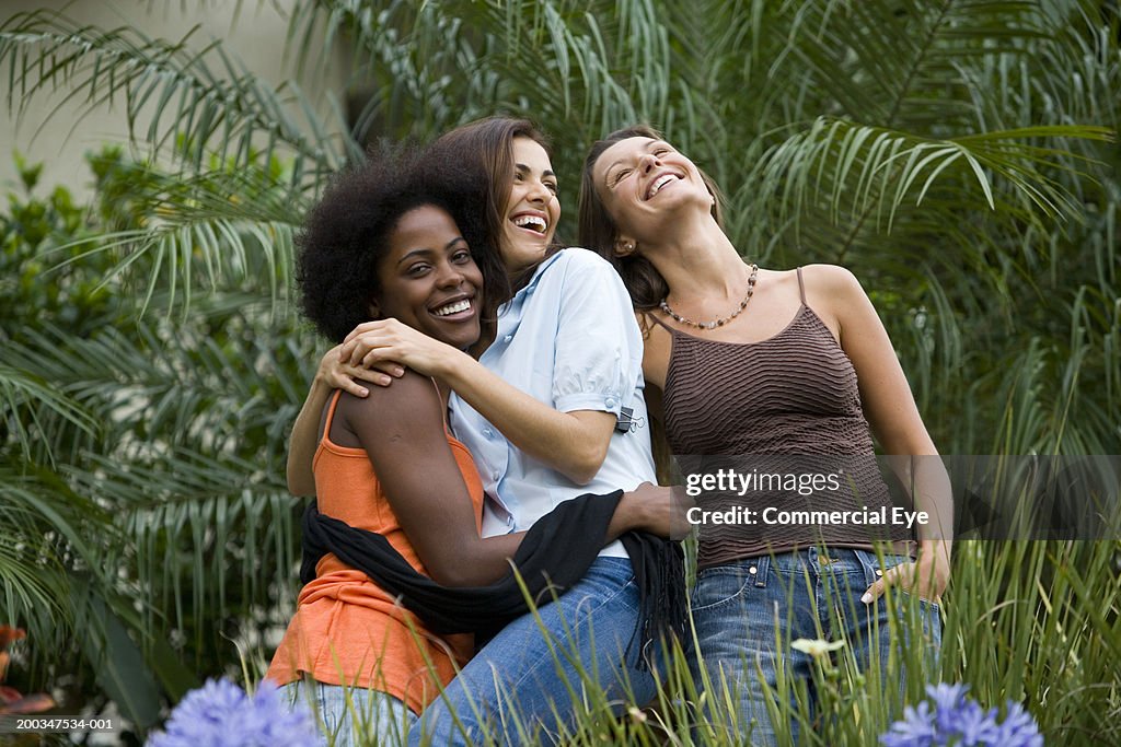 Three women standing in garden, smiling, portrait, close-up