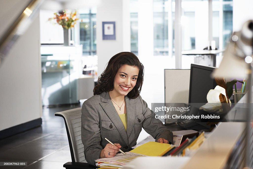 Businesswoman at desk, smiling, portrait