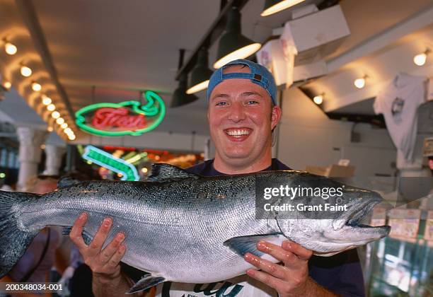 fishmonger holding wild salmon, portait - viswinkel stockfoto's en -beelden