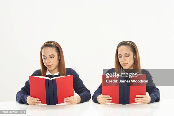 twin sisters reading books, wearing school uniforms - twin girls stock pictures, royalty-free photos & images