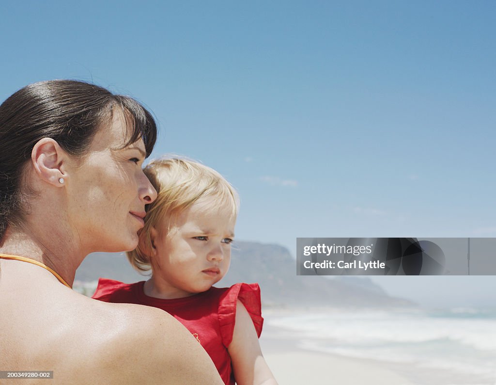 Woman holding baby daughter (12-15 months) on beach, close-up