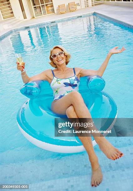 senior woman relaxing on float in swimming pool, portrait - alte frau badeanzug stock-fotos und bilder