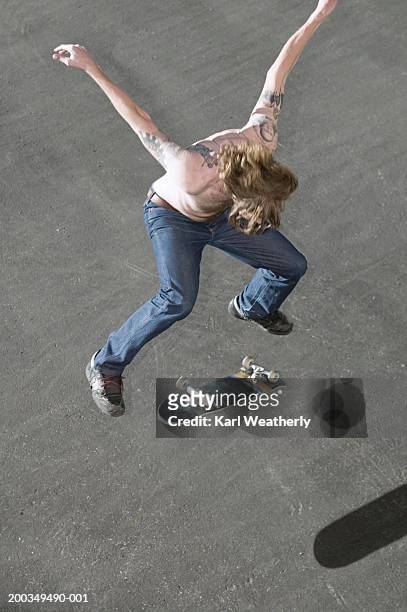 young man jumping with skateboard, arms outstretched, overhead view - gestalt stock-fotos und bilder