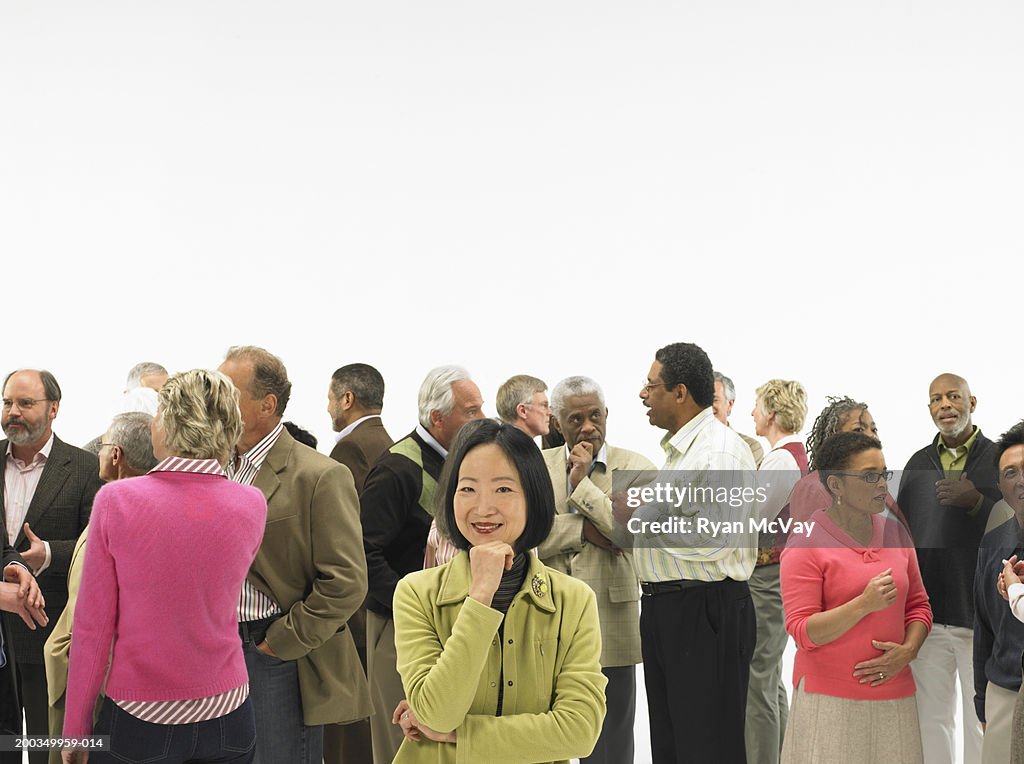 Group of mature men and women conversing, woman with hand on chin