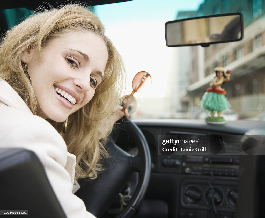Young woman in driver's seat of car smiling, portrait