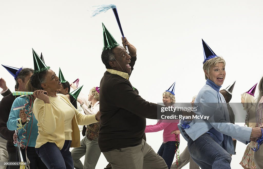 Group of mature men and women with party accessories, dancing