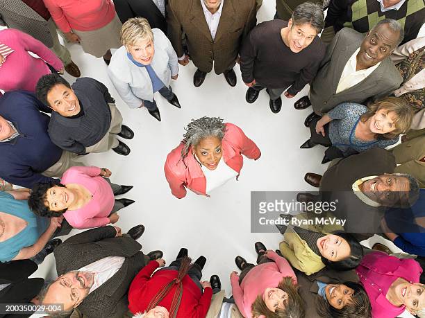 group of mature men and women standing in circle around woman - circondare foto e immagini stock