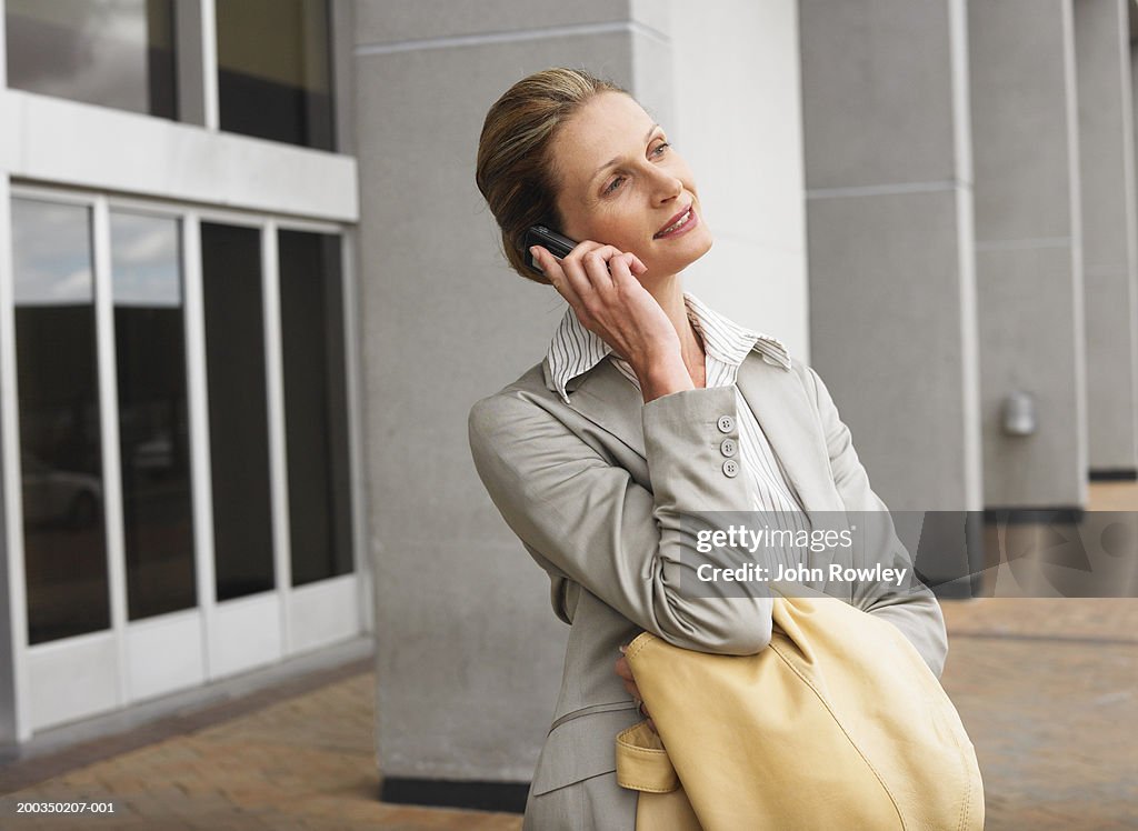 Businesswoman using mobile phone outdoors, smiling