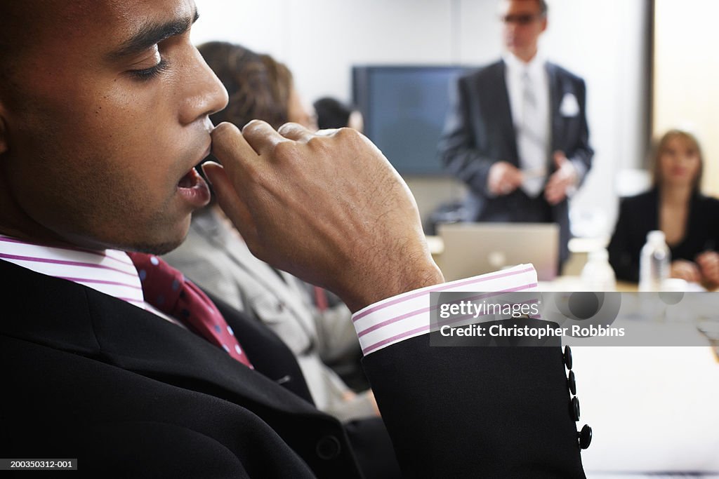 Businessman yawning in meeting, close-up