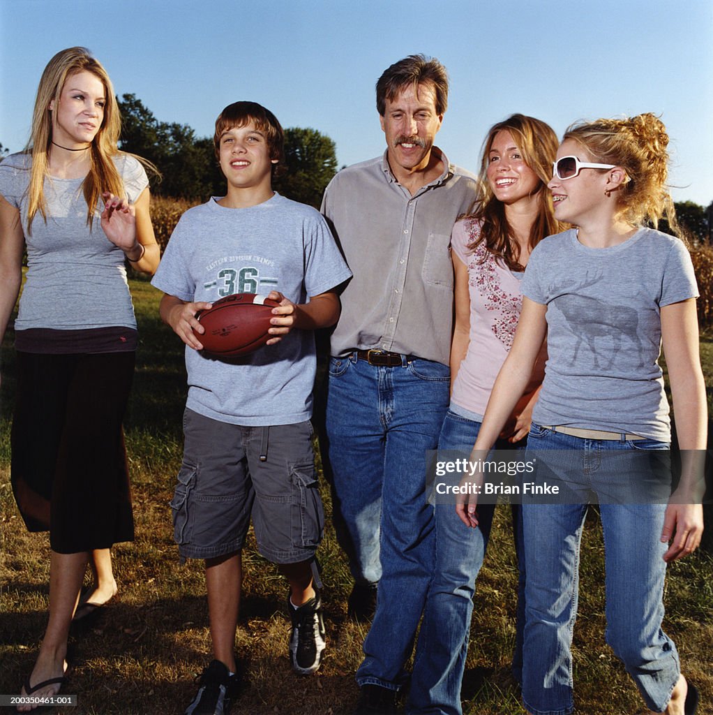 Father and teenage children (12-19) walking in backyard
