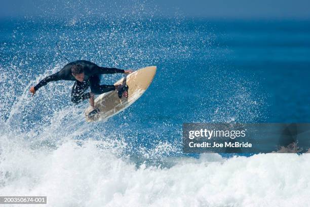 male surfer performing aerial manoeuver above wave - exploit sportif photos et images de collection