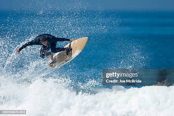 male surfer performing aerial manoeuver above wave - stunt stock pictures, royalty-free photos & images