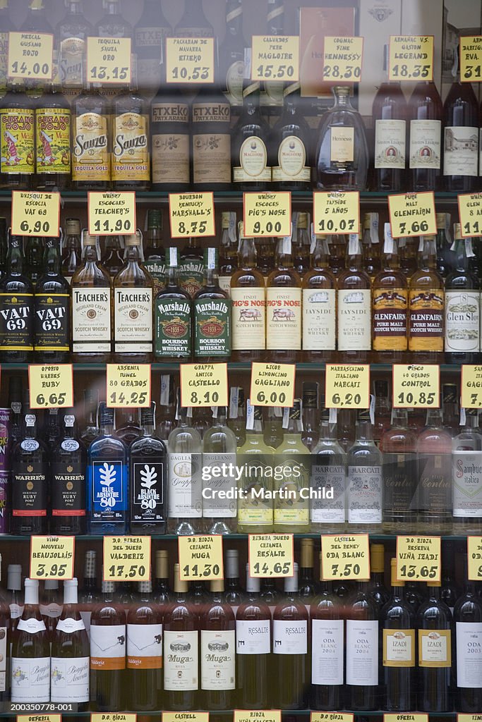 Various spirits and liqueurs in shop window, view through glass