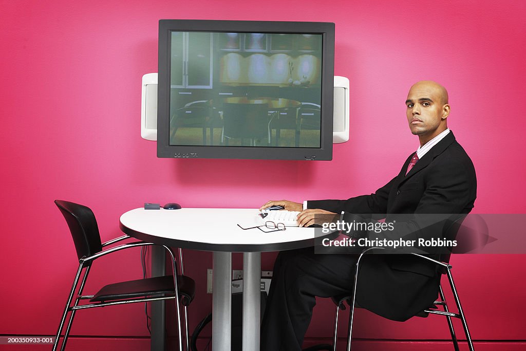 Businessman at table by flatscreen, portrait