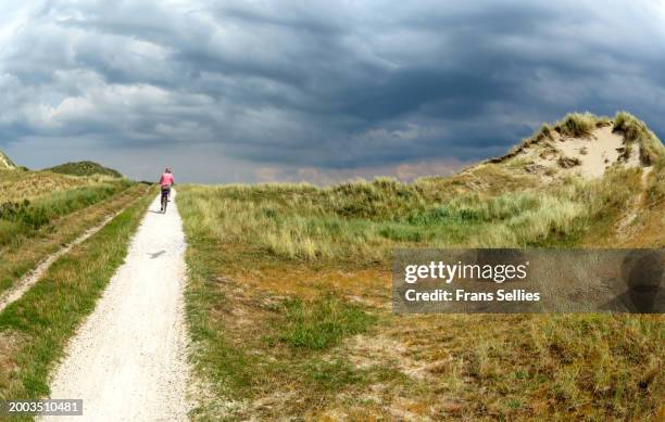 a cycling tourist exploring the beautiful landscape of vlieland, the netherlands - vlieland stock pictures, royalty-free photos & images