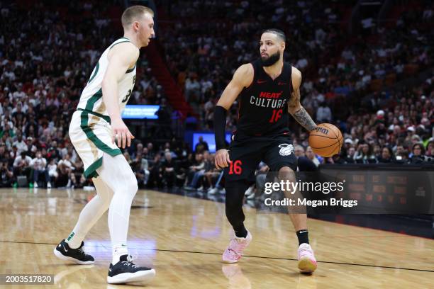 Caleb Martin of the Miami Heat dribbles the ball against Sam Hauser of the Boston Celtics during the fourth quarter of the game at Kaseya Center on...