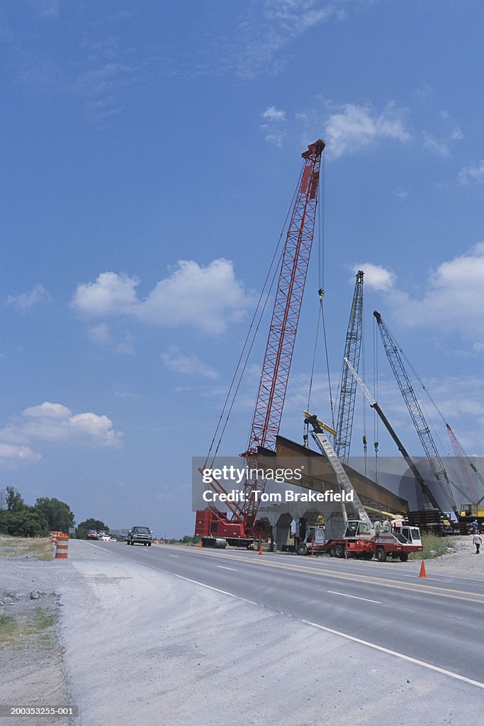 Cranes on road lifting steel plate girders, heavy construction, road building