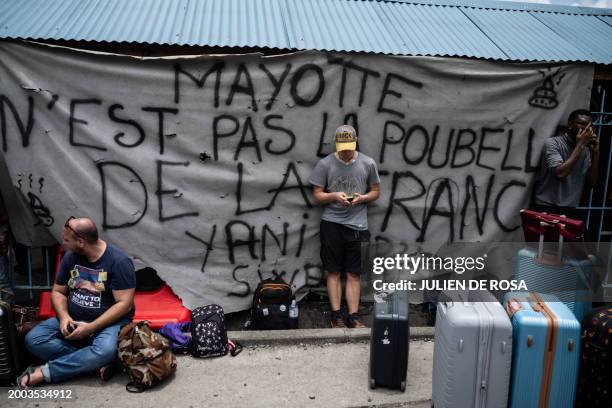 People wait for a boat at the barrage in the port of Dzaoudzi blocked to protest against living conditions and insecurity on the island of Mayotte,...