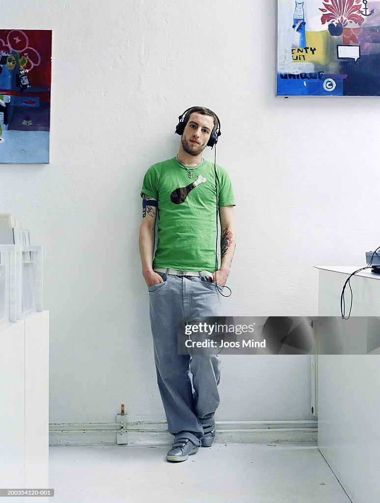 Young man wearing headphones with hands in pockets, portrait