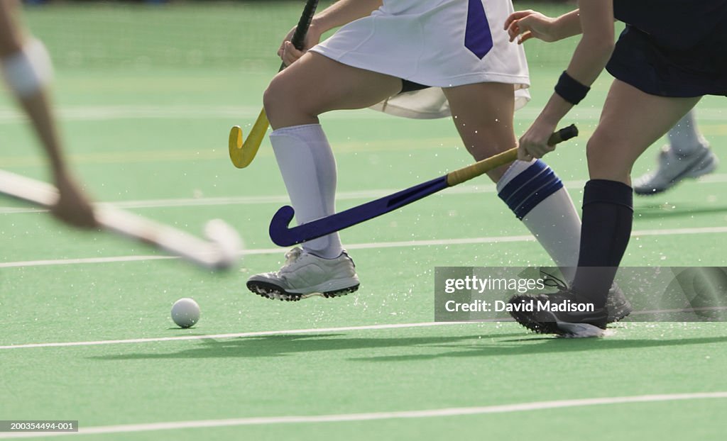 Women's field hockey players in action, low section