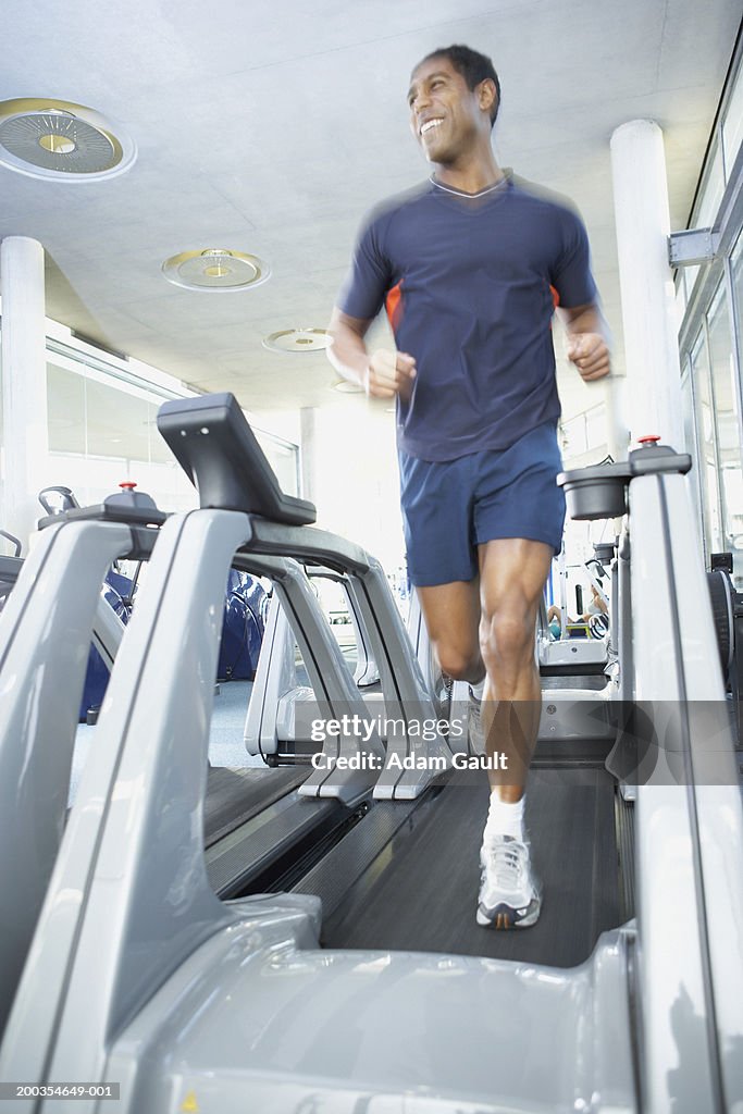 Mature man running on treadmill smiling (blurred motion)