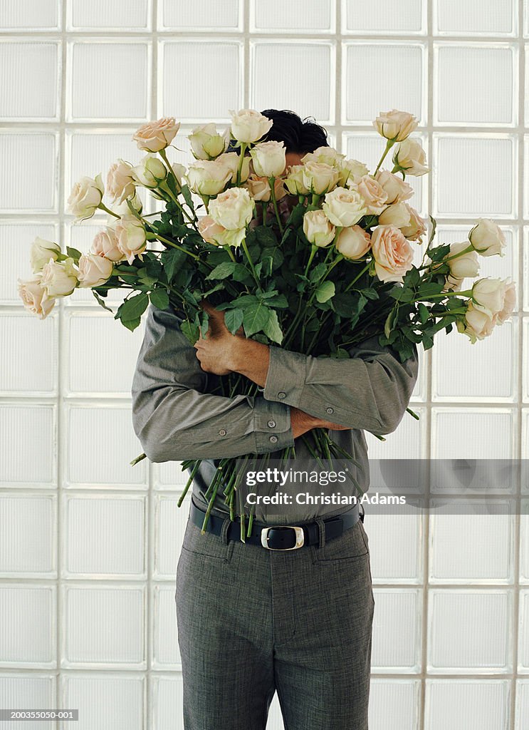 Man holding large bunch of white roses, face obscured