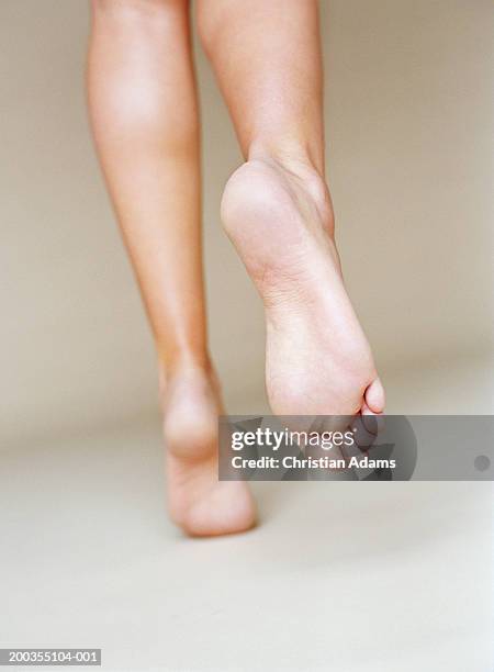 young woman with bare feet and legs, running, rear view, close-up - voetzool stockfoto's en -beelden