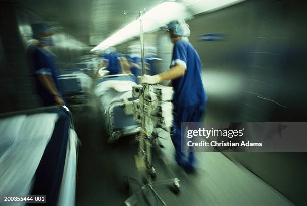 hospital staff pushing gurney and equipment in hallway(blurred motion) - urgency stock pictures, royalty-free photos & images