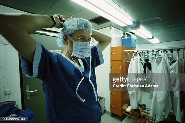 male surgeon putting on mask in changing room, close-up - get dressed male stock-fotos und bilder