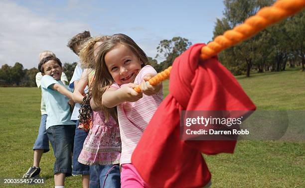 team of children (6-7 years) playing tug of war in park - lucha de la cuerda fotografías e imágenes de stock