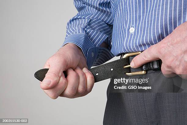 businessman fastening belt, mid section, close-up - fastening stockfoto's en -beelden