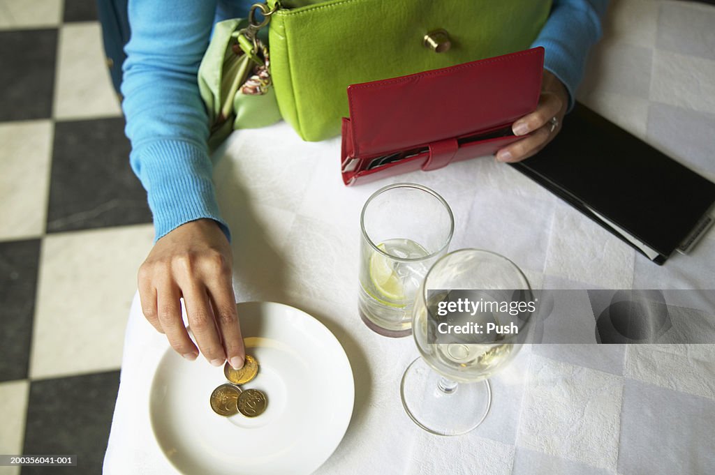 Woman leaving tip in restaurant, overhead view