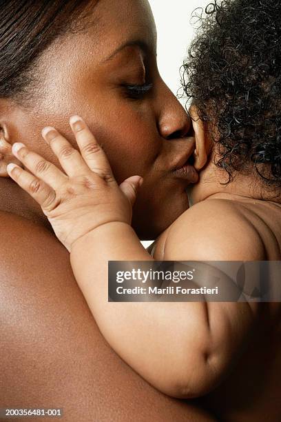 young woman kissing baby girl (6-9 months), side view, close-up - baby skin fotografías e imágenes de stock