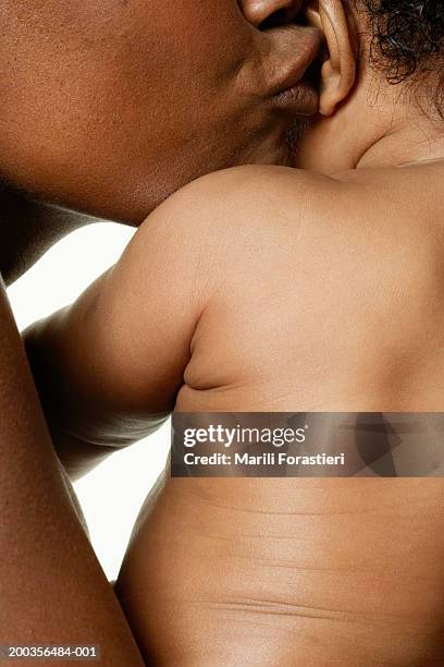 mother kissing baby girl (6-9 months) on ear, side view, close-up - baby skin fotografías e imágenes de stock