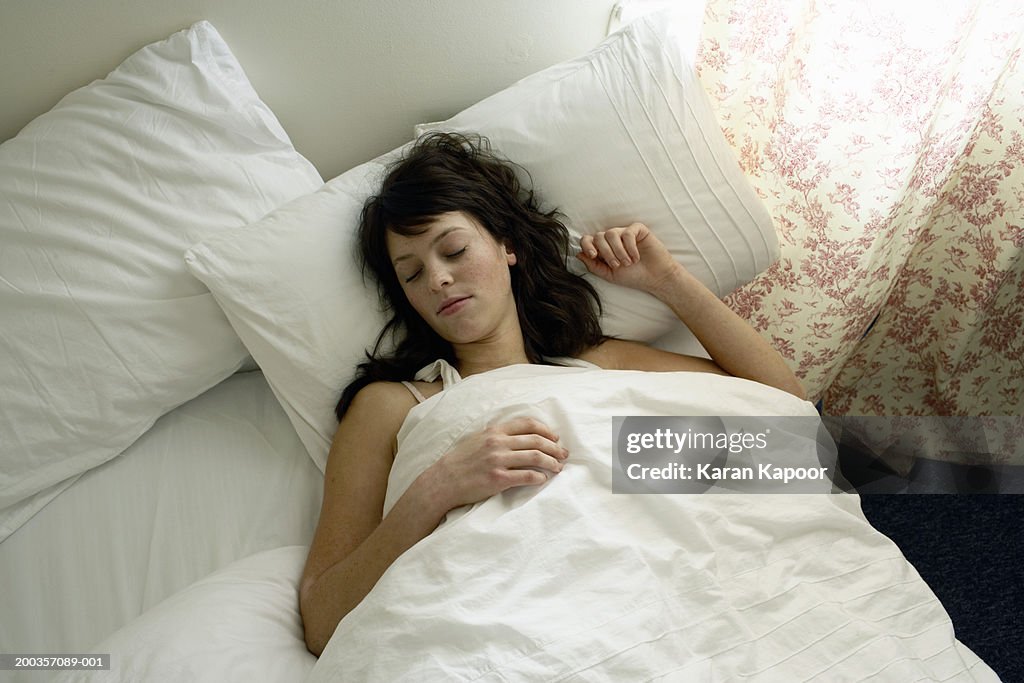 Young woman asleep in bed, close-up, elevated view