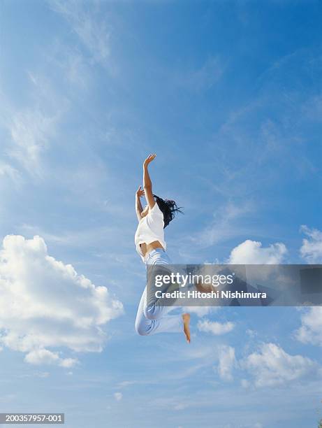 young woman jumping outdoors, low angle view - close to stock pictures, royalty-free photos & images
