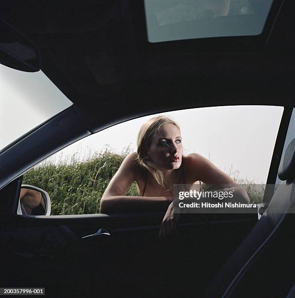 young woman leaning on car window, looking away - peep window stock-fotos und bilder