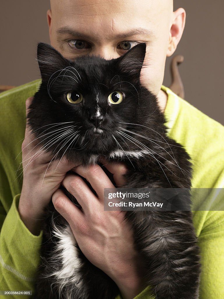 Man holding cat in front of face