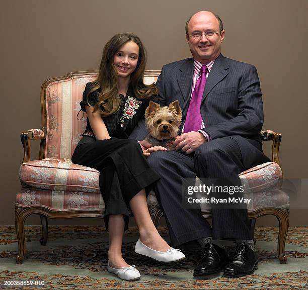 father and daughter (11-13) with dog sitting on love seat, portrait - well dressed dog stock pictures, royalty-free photos & images