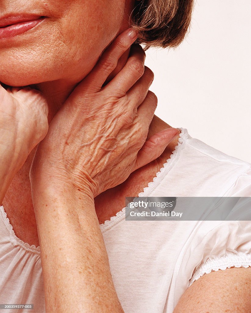 Senior woman holding hands to neck, close-up