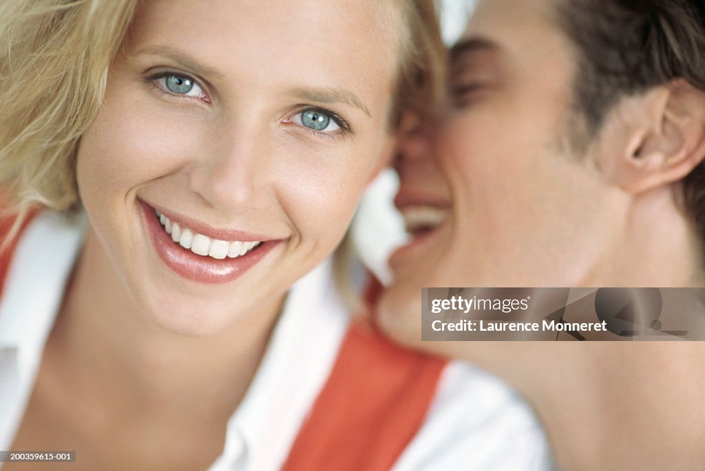 Young man laughing in woman's ear, portrait, close-up