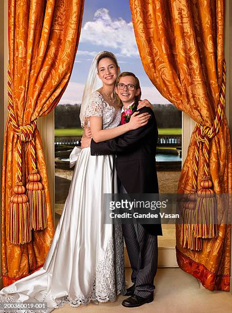 bride and groom embracing in front of window, smiling, portrait - bride and groom looking at camera stock-fotos und bilder