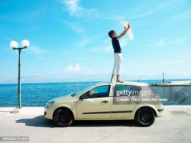 young man standing on car, looking at map, side view - eastern europe ストックフォトと画像