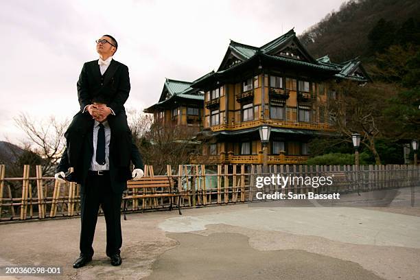 businessman sitting on man's shoulders - person auf den schultern tragen stock-fotos und bilder