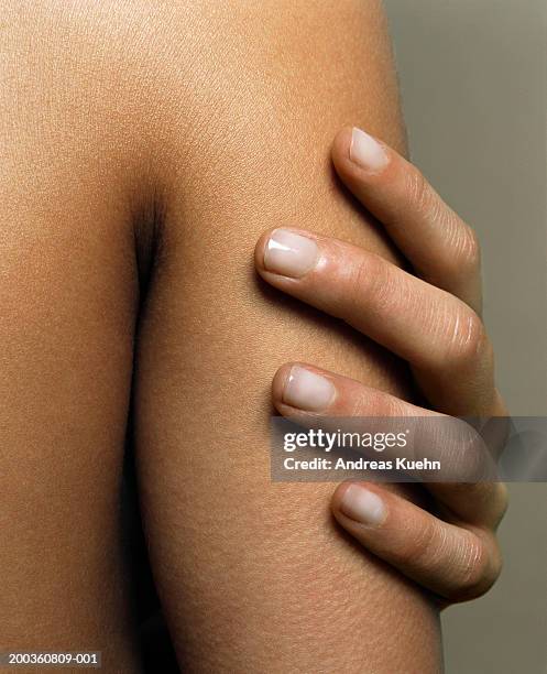 woman touching arm, close-up - berühren stock-fotos und bilder