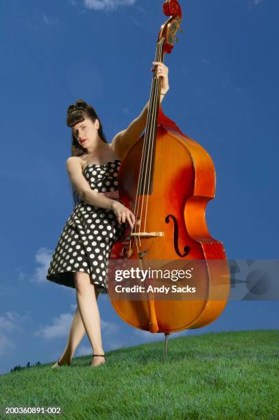 woman playing double bass on grassy hillside, portrait - double bass stock pictures, royalty-free photos & images