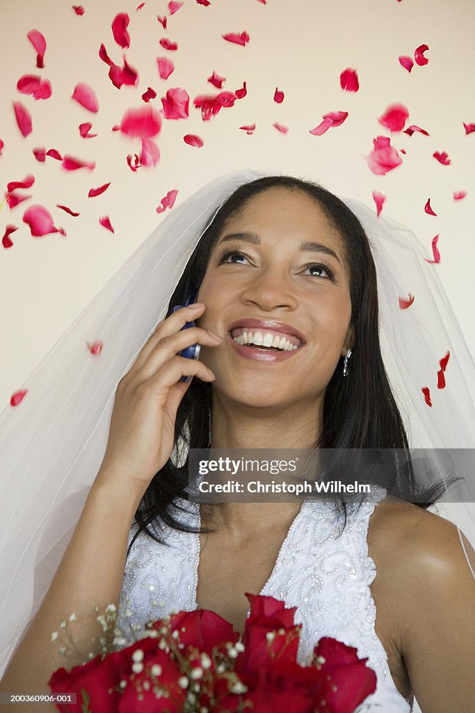 Rose petals falling on bride using mobile phone