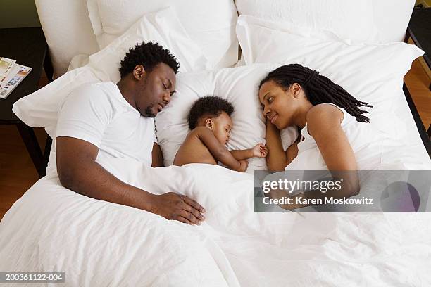 baby girl (8-11 months) sleeping on bed with mother and father - black man sleeping in bed stock pictures, royalty-free photos & images