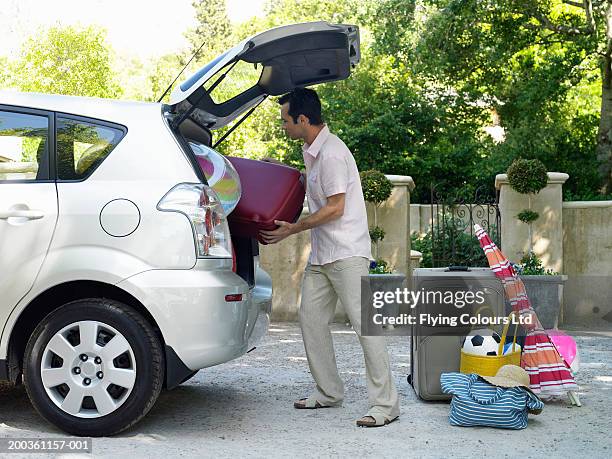 man putting suitcases into boot of car, side view - car sunshade stock pictures, royalty-free photos & images